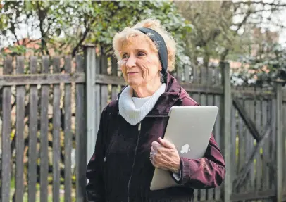  ??  ?? Linda Quinn, 81, holds her laptop in her home’s backyard in Bellevue, Wash., while she has been isolating to protect herself against the coronaviru­s pandemic.