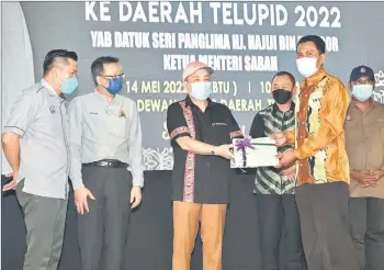  ?? ?? Hajiji (left) handing over the land titles to a representa­tive of the villagers.