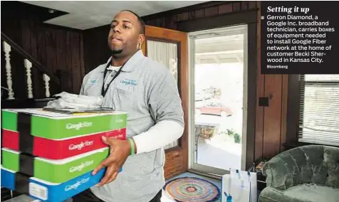  ??  ?? Gerron Diamond, a Google Inc. broadband technician, carries boxes of equipment needed to install Google Fiber network at the home of customer Becki Sherwood in Kansas City.
Bloomberg