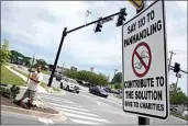  ?? MARK HUMPHREY / AP ?? Adam Atnip, who is homeless and lives in his car, panhandles near a sign asking people not to give directly to panhandler­s on May 10 in Cookeville, Tenn.