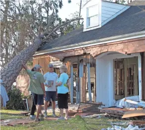  ??  ?? Rex Buzzett, far left, his son Josh Buzzett and neighbor Hilda Duren stand Thursday outside the Buzzetts’ home in Port St. Joe, Fla., that was gutted by the storm surge from Hurricane Michael.