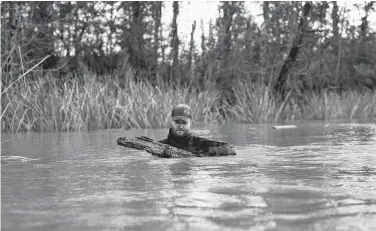  ?? Daniel Fiore / Associated Press ?? Maritime archaeolog­ist Kyle Lent examines a wooden plank from the hull of Clotilda, in delta waters north of Mobile Bay, Ala. Using detailed archival records of more than 1,500 ship registries, researcher­s determined the half-buried ship was the exact size and shape of the Clotilda.