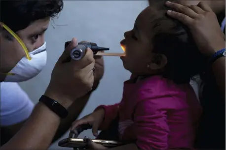  ?? GREGORY BULL — THE ASSOCIATED PRESS ?? this photo, dentist Demetrio Cardenas, left, checks inside the mouth of a patient in a shelter for migrants in Tijuana, Mexico The health crisis spans both sides of the border. In the past year, at least three children, detained by U.S. Border Patrol agents, have died from the flu while being held. They include a 16-year-old boy who was seen on security footage writhing in agony on the floor in a U.S. Border Patrol holding cell.