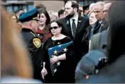  ?? ANTONIO PEREZ/CHICAGO TRIBUNE ?? Becki Keltner holds onto a U.S. flag March 13 as pallbearer­s carry out the casket of her husband, Deputy Jacob Keltner.