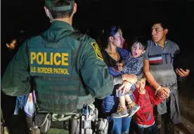  ?? JOHN MOORE / TNS ?? Immigrants wait for a U.S. Border Patrol agent to lead them up from the bank of the Rio Grande after they crossed the U.S.-Mexico border on April 14 in Roma, Texas. A surge of mostly Central American immigrants crossing into the United States, including record numbers of children, has challenged U.S. immigratio­n agencies along the border.