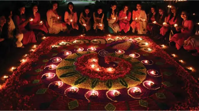  ??  ?? Indian girls light earthen lamps on a Rangoli as they celebrate Diwali, the Festival of Lights, in Guwahati. — AFP