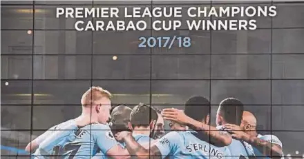  ?? AFP PIC ?? A new poster showing Manchester City players celebratin­g has been placed at the entrance to the Etihad Stadium after the club won the Premier League title on Sunday.