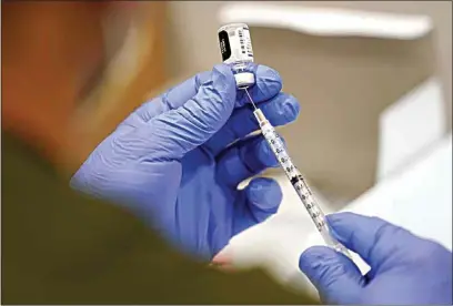  ?? LYNNE SLADKY / AP FILE ?? In this Oct. 5 file photo, a healthcare worker fills a syringe with the Pfizer COVID-19 vaccine at Jackson Memorial Hospital in Miami. President Joe Biden’s most aggressive move yet to combat the COVID-19 pandemic is almost ready to see the light of day. The government is close to publishing the details of a new vaccinatio­n-or-testing rule covering more than 80 million Americans at companies with 100 or more workers.