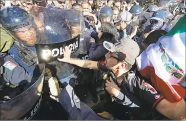  ?? Luis Sinco Los Angeles Times ?? PROTESTERS clash with police outside the Tijuana facility where Central American migrants are staying.