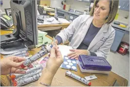  ?? KAREN KASMAUSKI/THE NEW YORK TIMES ?? Diane Voelker, a school nurse, and her assistant, Beth Little, look over EpiPens at Stone Bridge High School in Ashburn, Va., Aug. 31, 2012. In another move to quell outrage over its price increases, the maker of the EpiPen said Monday, that it would...