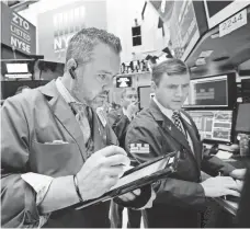  ?? RICHARD DREW, AP ?? Traders examine data at the New York Stock Exchange on Thursday. The Dow has made little progress since 2014.