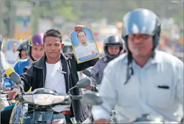  ?? HONG MENEA ?? A man holds a poster of Pen Sovann yesterday as he travels to Phnom Penh with the former prime minister’s procession.