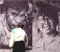  ?? — Reuters photo ?? A man writes a goodwill message on a poster depicting detained Reuters reporters Wa Lone and Kyaw Soe Oo at an event discussing press freedom, in Yangon, Myanmar.