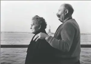  ?? The Associated Press ?? THE NEW COLOSSUS: Mr. and Mrs. Paul Roerich from Bavaria, Germany, looking out from the stern of the USNS General Langfitt on Oct. 28, 1956, anchored in New York Harbor carrying over a 1,000 refugees from Europe. In the background is the Statue of Liberty. The couple planned to settle in Ohio.