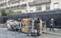  ?? REUTERS ?? Vandalized cars are seen on Avenue Foch the morning after clashes with protesters wearing yellow vests, a symbol of a French drivers' protest against higher diesel taxes, in Paris on Sunday. &gt;&gt;P12