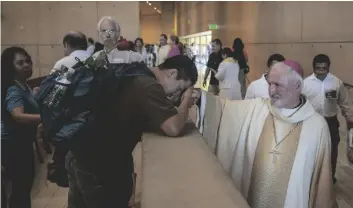  ?? AP PHOTO/DAMIAN DOVARGANES ?? Auxiliary Bishop David O’Connell (right) from the San Gabriel Pastoral Region, is revered by an unidentifi­ed pilgrim (left) after a special “Mass in Recognitio­n of All Immigrants’’ at the Los Angeles Cathedral of Our Lady of Angels in Los Angeles in 2018.