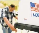  ?? AMY DAVIS/BALTIMORE SUN ?? Ken Kondner, an election board judge, moves a voting machine into position Wednesday at the Randallsto­wn Community Center, an early voting site.