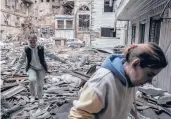  ?? FINBARR O’REILLY/THE NEW YORK TIMES ?? Two women survey the wreckage of an apartment building Monday after a Russian bombardmen­t in Kharkiv, Ukraine.