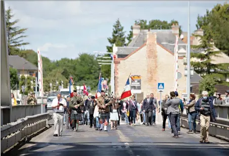  ?? AP Photo/Virginia Mayo ?? British expatriate Steven Oldrid, left, prepares to film a group crossing over the site of the original WWII Pegasus Bridge during D-Day ceremonies June 6 in Benouville, Normandy, France.