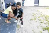  ??  ?? Bathsheba Collingwoo­d ties her son’s shoes in front of their apartment in Orlando on April 6.