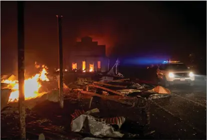  ?? KARL MONDON — BAY AREA NEWS GROUP FILE ?? A Plumas County Sheriff's Office deputy drives past devastatio­n at the intersecti­on of Main Street and Highway 89in Greenville, Aug. 4, 2021, after it was destroyed by the Dixie Fire.