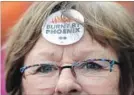  ?? JUSTIN TANG THE CANADIAN PRESS ?? A woman wears a “Burnt by Phoenix” sticker at a rally against the payroll system.