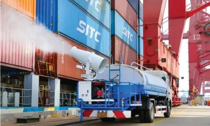  ?? Photograph: VCG/Getty Images ?? A vehicle sprays disinfecta­nt on shipping containers to prevent the spread of Covid-19 at Lianyungan­g port in China. The country’s export growth hit a near two-year low of 3.9% a year in April.
