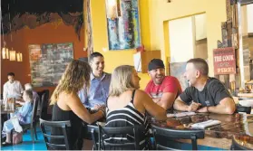  ??  ?? Above: Fenix restaurant manager Ruben Baumback, center, chats with a group of regular customers. Left: A burrata caprese salad with a balsamic glaze sits on a table during lunch at Pietro’s Trattoria.