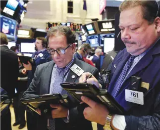  ??  ?? NEW YORK: Traders work on the floor of the New York Stock Exchange on Friday. —AP