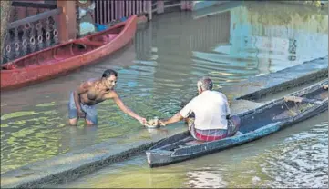  ?? BLOOMBERG ?? A man standing in floodwater shares tea with another man sitting in a canoe in Kerala’s Alappuzha district.