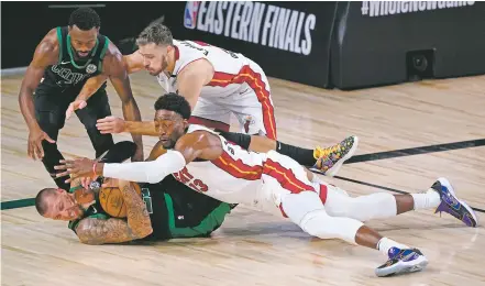  ?? PHOTOS BY MARK J. TERRILL/ASSOCIATED PRESS ?? The Celtics’ Kemba Walker, top left, and Daniel Theis, bottom left, battle for a loose ball against the Heat’s Goran Dragic, top right, and Bam Adebayo on Thursday in Lake Buena Vista, Fla. The Heat rallied from 17 points down in the second quarter to win.