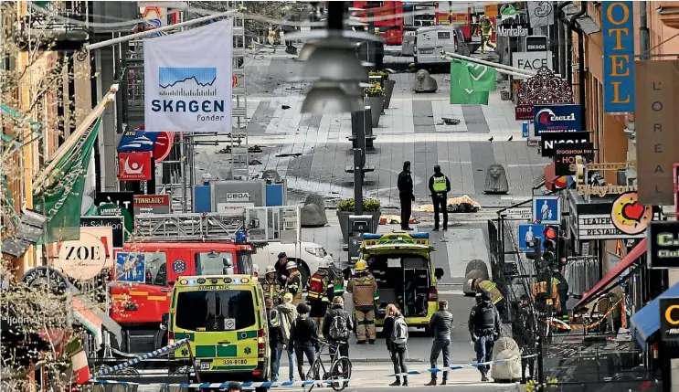  ??  ?? Emergency services workers swarm in central Stockholm yesterday after a man hijacked a truck and crashed it into a crowd.