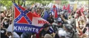  ?? STEVE HELBER — THE ASSOCIATED PRESS ?? This July 8 photo shows members of the KKK escorted by police past a large group of protesters during a KKK rally in Charlottes­ville, Va.