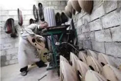  ??  ?? A Syrian worker sands a oud.