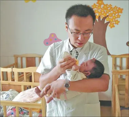  ?? PROVIDED TO CHINA DAILY ?? Yuan Dong takes care of a baby at Luohe Welfare House, Henan province.