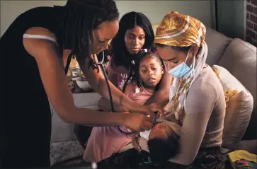  ?? PHOTOS BY SARAH REINGEWIRT­Z — STAFF PHOTOGRAPH­ER ?? Aysha-Samon Stokes and daughter, Nyla, watch midwife Allegra Hill and student midwife Maryam Karim check the heartbeat of 2-week-old Nikko during a postpartum visit to the South L.A. birthing center where he was born on Mother’s Day.