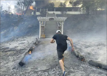  ?? WILL LESTER — STAFF PHOTOGRAPH­ER ?? Manny Hernandez rushes toward his burning home as fire smolders around him at Lytle Creek Road near Lytle Creek on Wednesday. Hernandez, who has lived at the home for 35years, was searching unsuccessf­ully for his family’s cats.