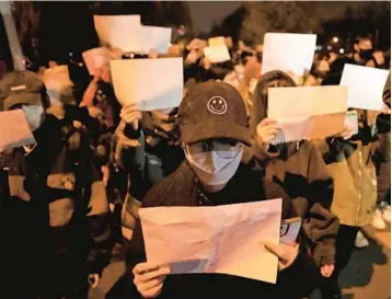  ?? NG HAN GUAN/AP ?? Protesters hold up blank sheets of paper, a symbol of defiance against China’s censorship, on Sunday in Beijing.