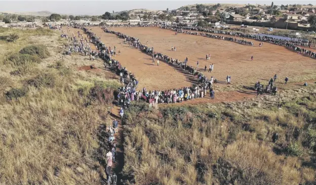  ?? PICTURE: MARCO LONGARI ?? 0 People queue during a distributi­on of hampers, masks, soap and sanitiser organised by charities near Pretoria in South Africa