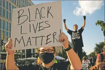  ??  ?? Antonio Mingo (right) of Washington holds his fists in the air June 24 as demonstrat­ors protest in front of a police line on a section of 16th Street that’s been renamed Black Lives Matter Plaza in Washington, following the death of George Floyd.
(File Photo/AP/Jacquelyn Martin)