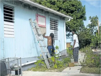  ?? LIONEL CHAMOISEAU/GETTY IMAGES ?? People put boards on their windows as part of preparatio­ns for arrival of hurricane Irma on Monday in Marigot, on the French island of Saint-Martin. Irma was expected to hit the Leeward Islands late Tuesday, with other Caribbean nations also in its path.