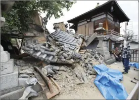  ??  ?? The gate of Myotoku-ji temple collapses after an earthquake hit Ibaraki City, Osaka, western Japan, on Monday. A strong earthquake knocked over walls and set off scattered fires around metropolit­an Osaka on Monday morning. YOSUKE MIZUNO/ KYODO NEWS VIA...