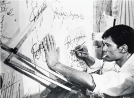  ?? HULTON ARCHIVE Getty Images/tns ?? French actor Alain Delon smokes a cigarette as he practices forging a signature in a still from the film “Purple Noon,” based on the Patricia Highsmith novel “The Talented Mr. Ripley” and directed by René Clément, 1960.