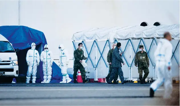  ?? Agence France-presse ?? ↑
Military officials and medical staff are seen near the quarantine­d cruise ship in Yokohama on Thursday.