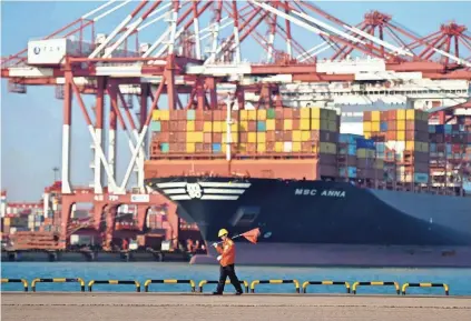  ?? CHINATOPIX VIA AP ?? A container ship is docked at a port in Qingdao in east China’s Shandong province. China’s economic growth slowed further in the latest quarter.