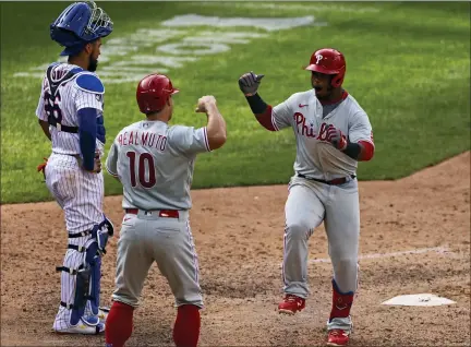  ?? ADAM HUNGER — THE ASSOCIATED PRESS ?? Philadelph­ia Phillies’ Jean Segura celebrates hitting a two-run home run with J.T. Realmuto (10) in front of New York Mets catcher Robinson Chirinos during the 10th inning of a baseball game on Monday in New York.