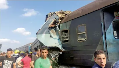  ?? Reuters ?? Egyptians look at the crash of two trains that collided near the Khorshid station in the coastal city of Alexandria on Friday. —