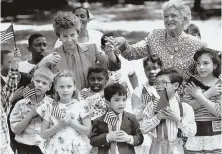  ?? HERALD FILE PHOTO ?? CLASS ACT: Barbara Bush and Raisa Gorbachev hold hands at the Public Garden with students from the Mather Public School in Dorchester during a 1990 visit to Boston.