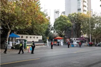  ?? — AFP photo ?? Police officers and medical staff members wearing personal protective equipment (PPE) are seen outside a residental area that is under restrictio­ns following a recent coronaviru­s outbreak in Shanghai.