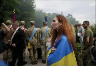  ?? NATACHA PISARENKO — THE ASSOCIATED PRESS ?? A woman wrapped in a Ukrainian flag attends the funeral of activist and soldier Roman Ratushnyi in Kyiv, Ukraine, Saturday. Ratushnyi died in a battle near Izyum, where Russian and Ukrainian troops are fighting for control of the area.